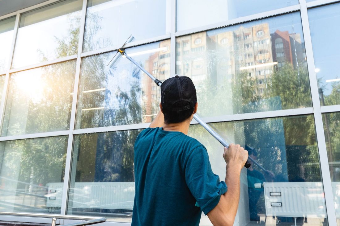 Person washing a glass building window with a squeegee outdoors