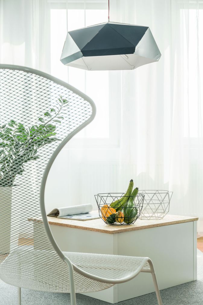Modern white chair beside a small table with fruit in a bright, minimalist room
