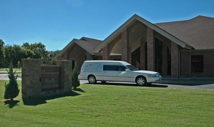 Brick building with white columns and a covered porch on a sunny day.