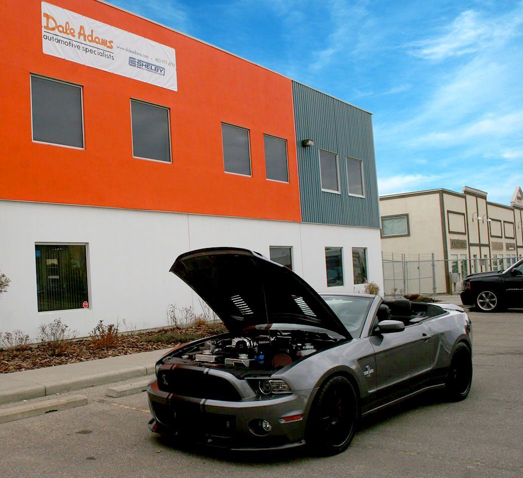 Black convertible with hood open parked on a street beside an orange-and-gray building | Dale Adams Automotive Specialists