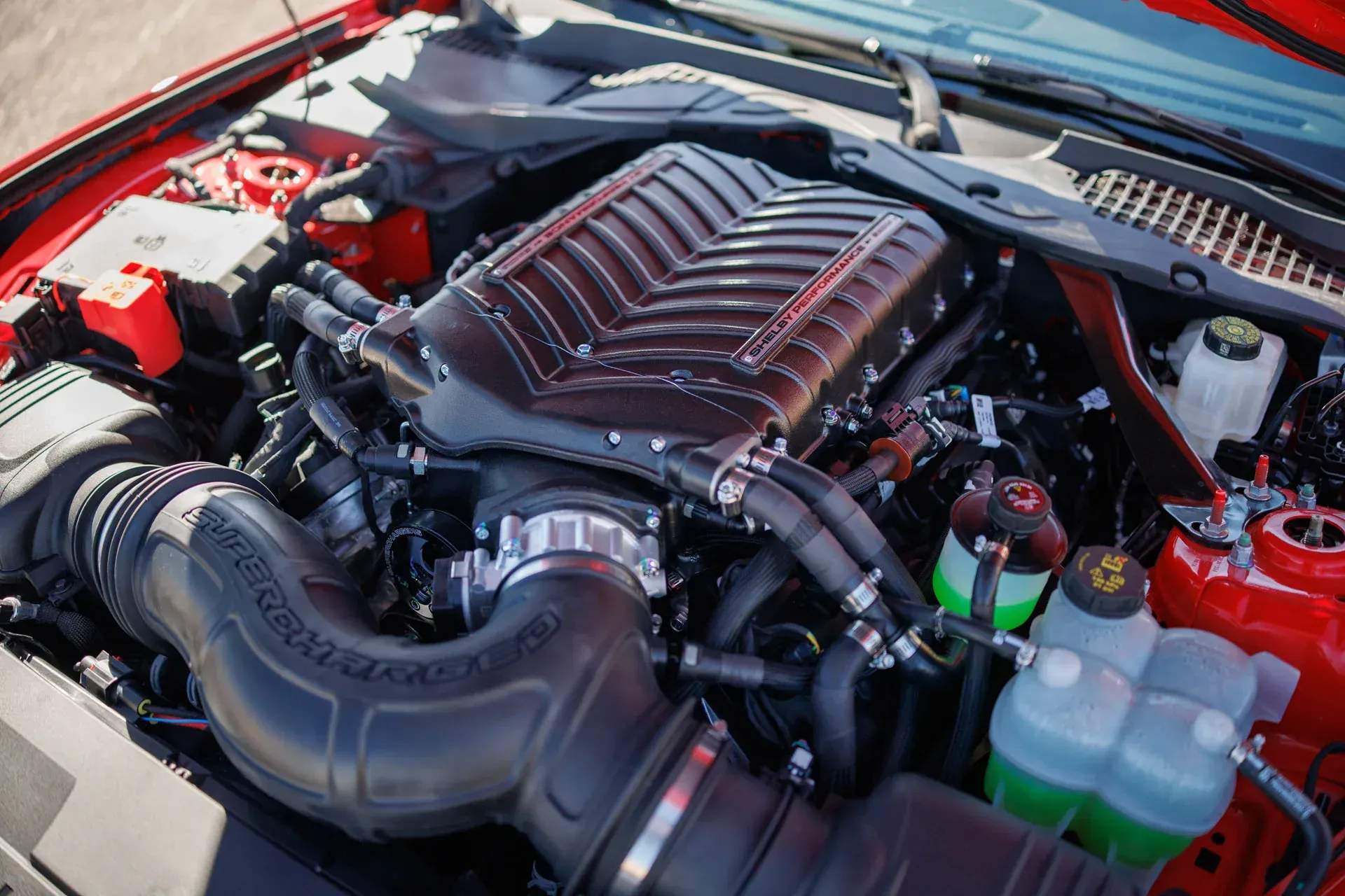 Close-up of a car engine bay with red body panels and a large black intake tube