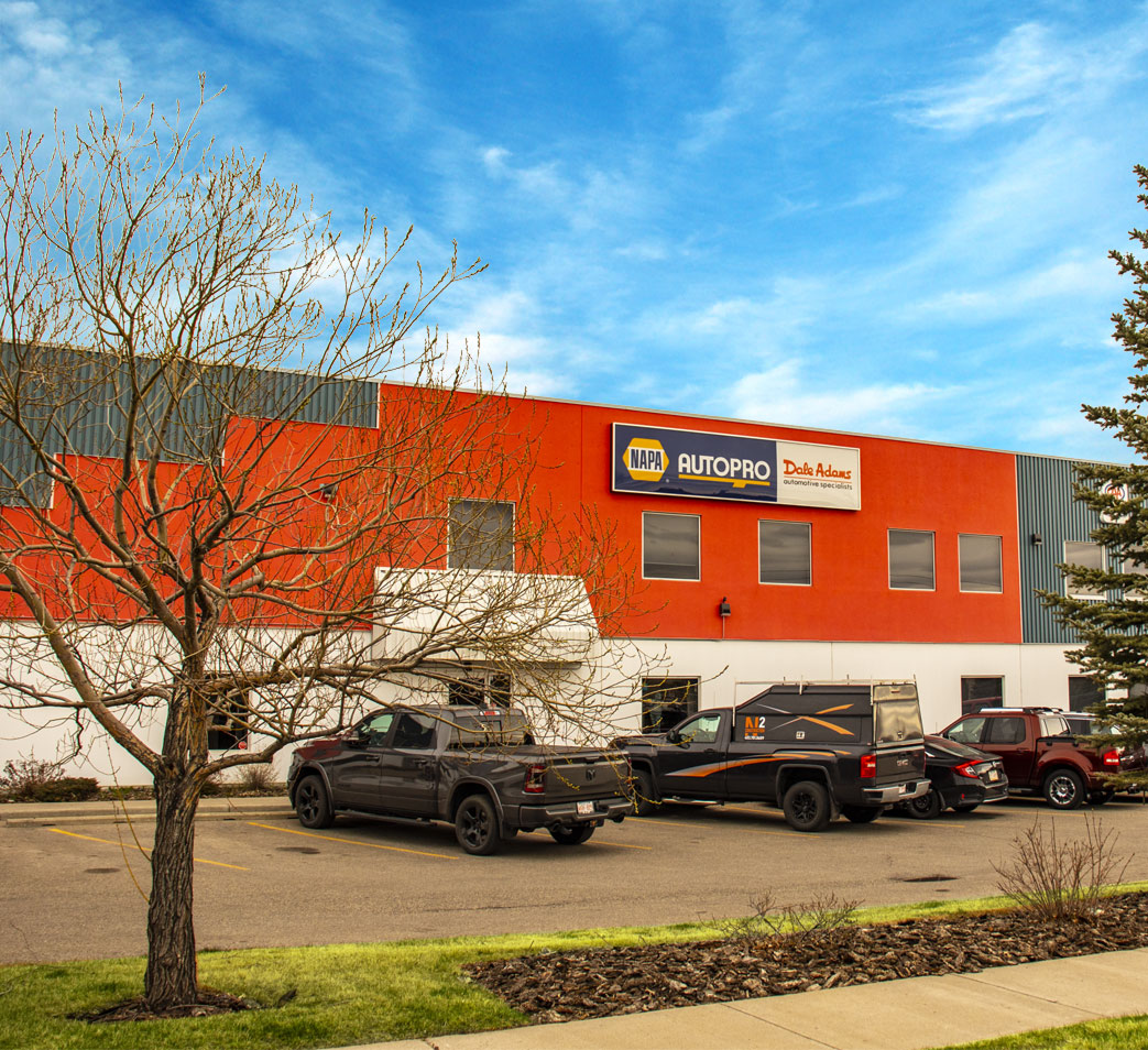 Orange commercial building with parked pickup trucks under a blue sky | Dale Adams Automotive Specialists
