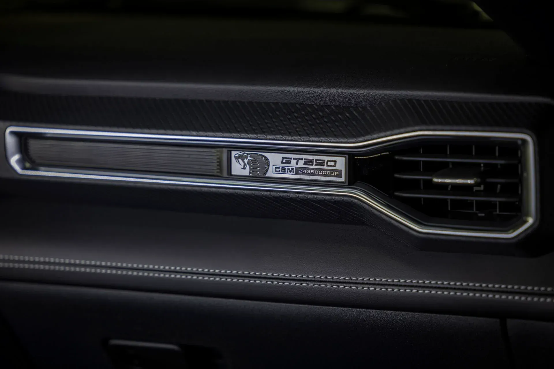 Close-up of a Jeep dashboard air vent with chrome trim and stitched black leather paneling