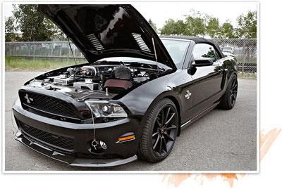 Black Ford Mustang with hood open, parked outdoors on pavement near a fence. | Dale Adams Automotive Specialists