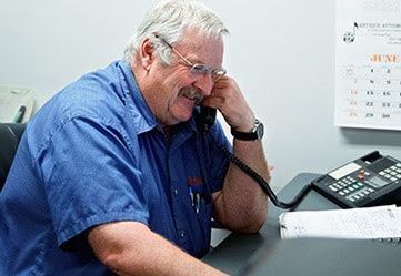 Smiling man talking on wire phone | Dale Adams Automotive Specialists