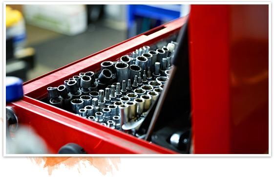 Red toolbox filled with socket wrenches and bits in a workshop drawer