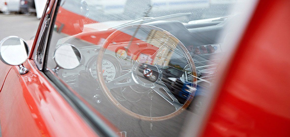 Red car interior with a close-up of the steering wheel and dashboard through the side window