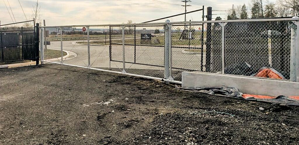 Chain-link fence surrounding an open area with a gravel ground, overcast sky.