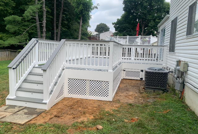 White and gray outdoor deck with stairs, built next to a house with an air conditioning unit.