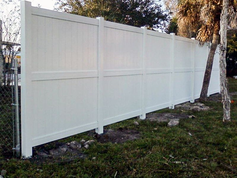 White vinyl privacy fence in a grassy yard.