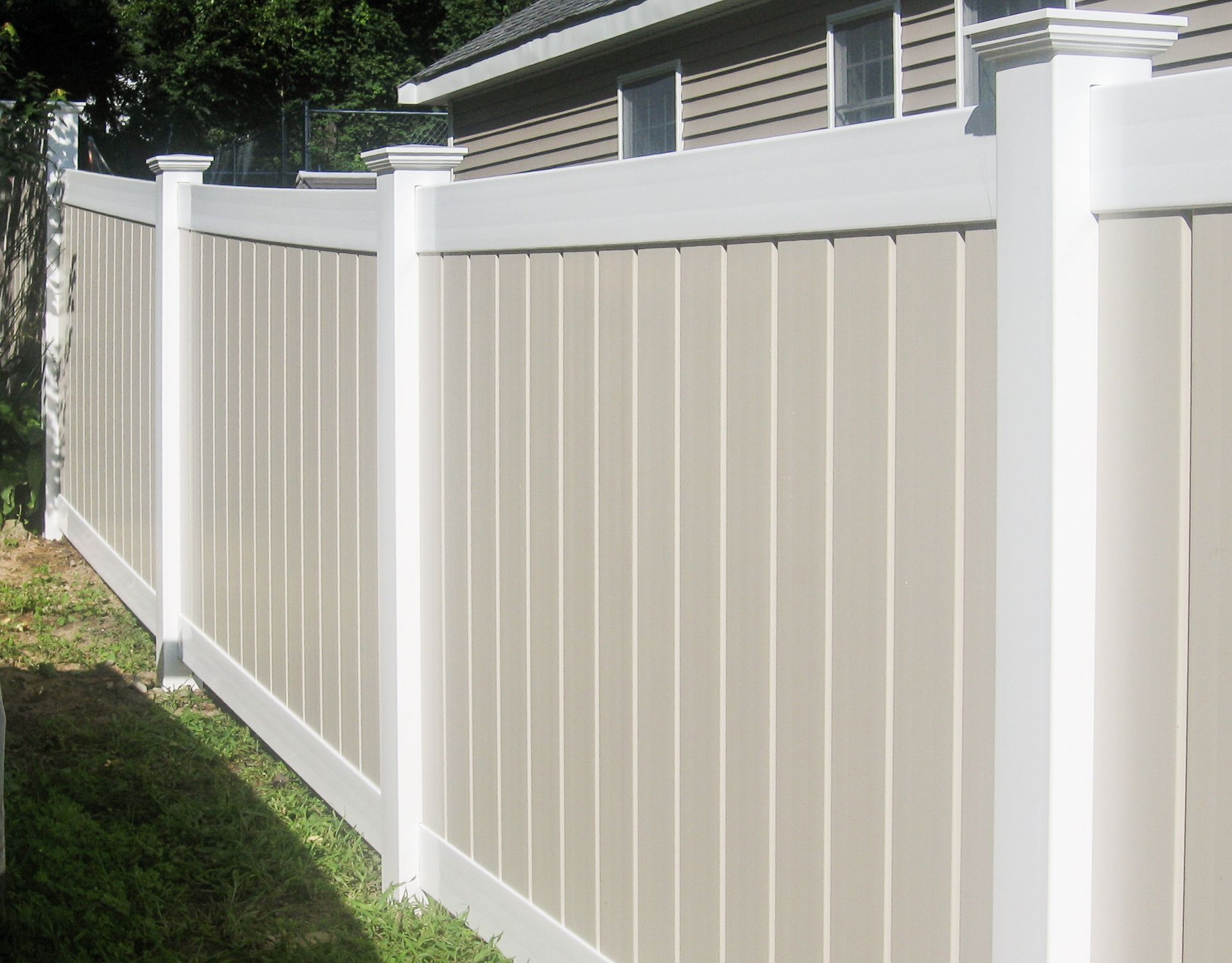 Tan and white vinyl privacy fence in a grassy yard.