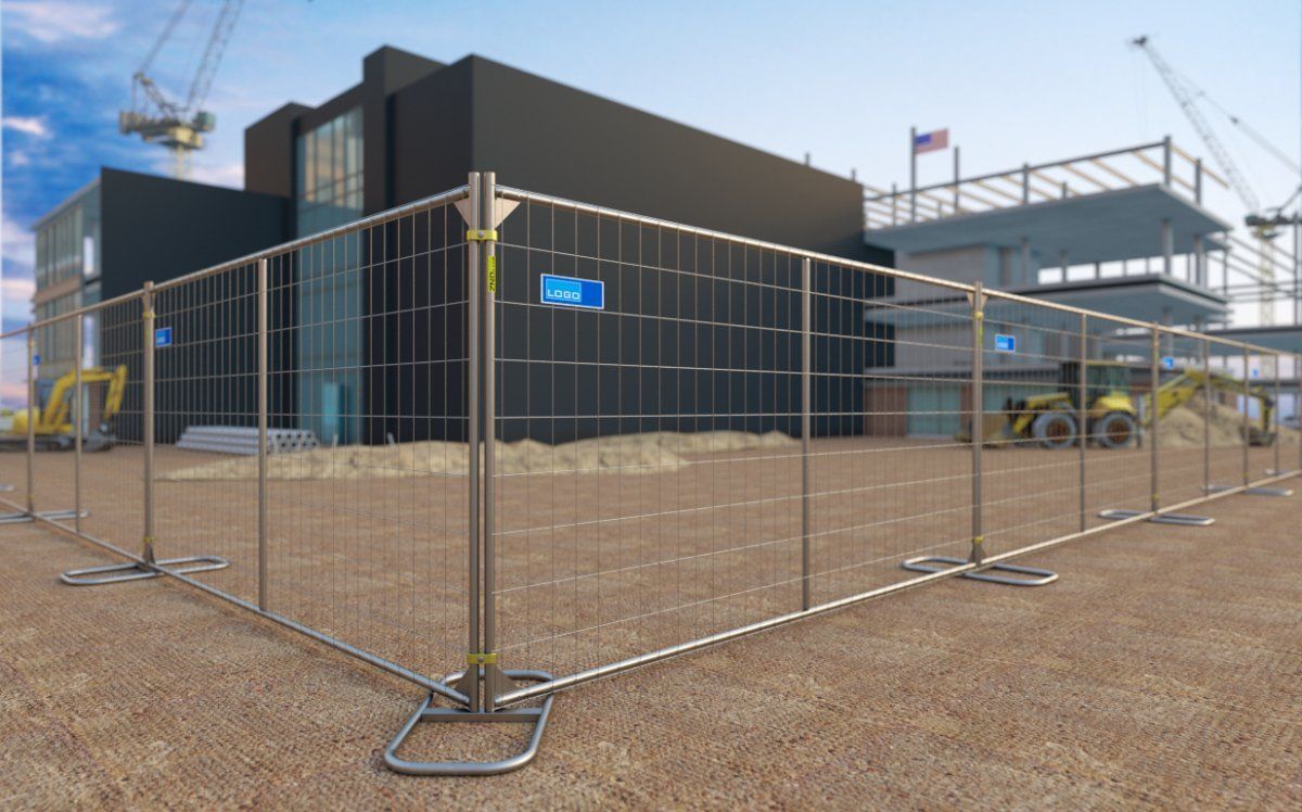 Construction site fenced off, with building and equipment in the background.