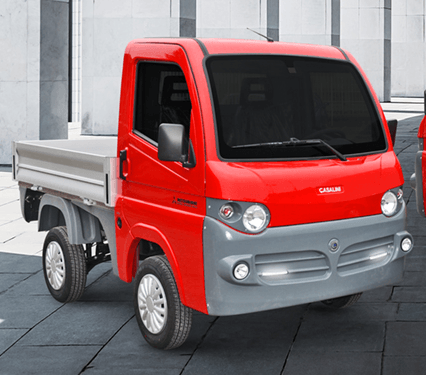 Camion compatto rosso con pianale in un ambiente industriale grigio.