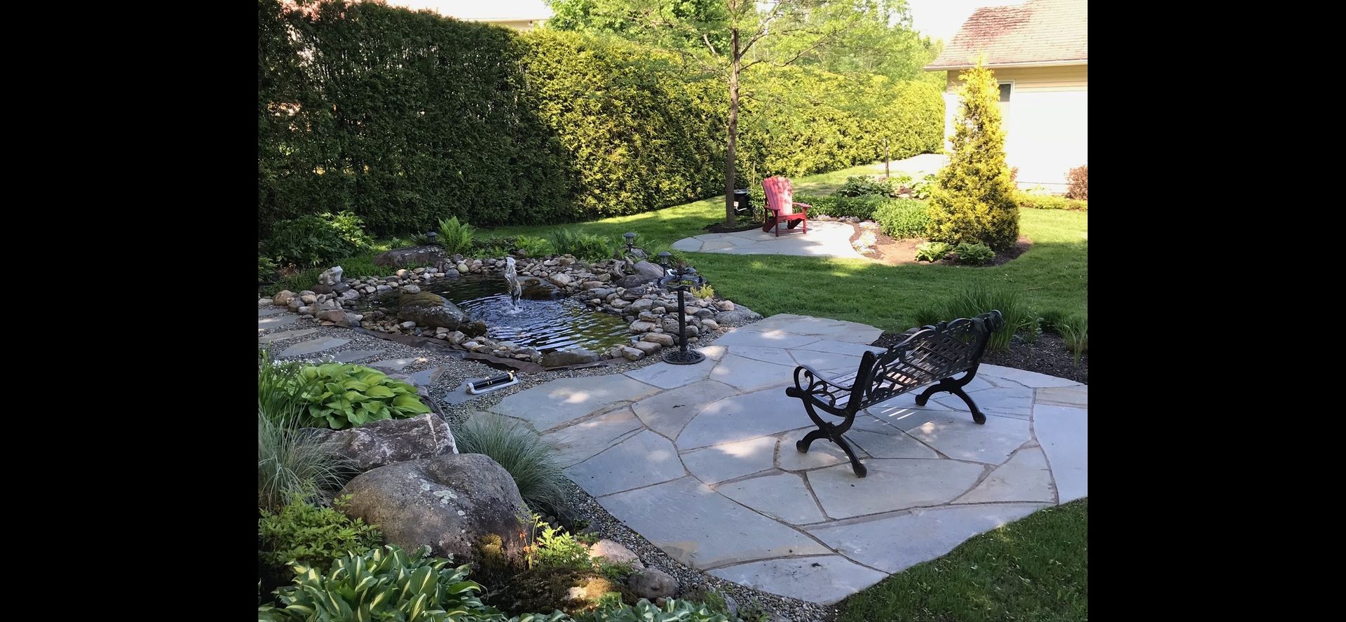 Un patio avec un banc et une fontaine dans l'arrière-cour d'une maison.