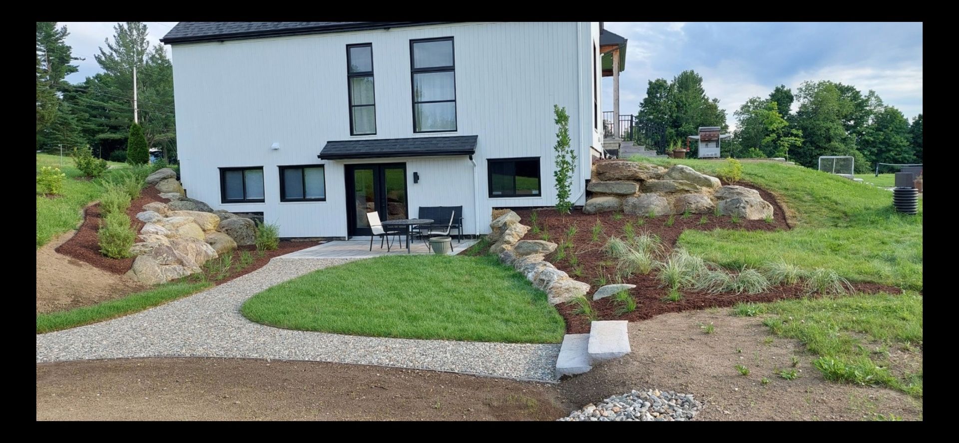 Une maison blanche est assise au sommet d'une colline herbeuse.