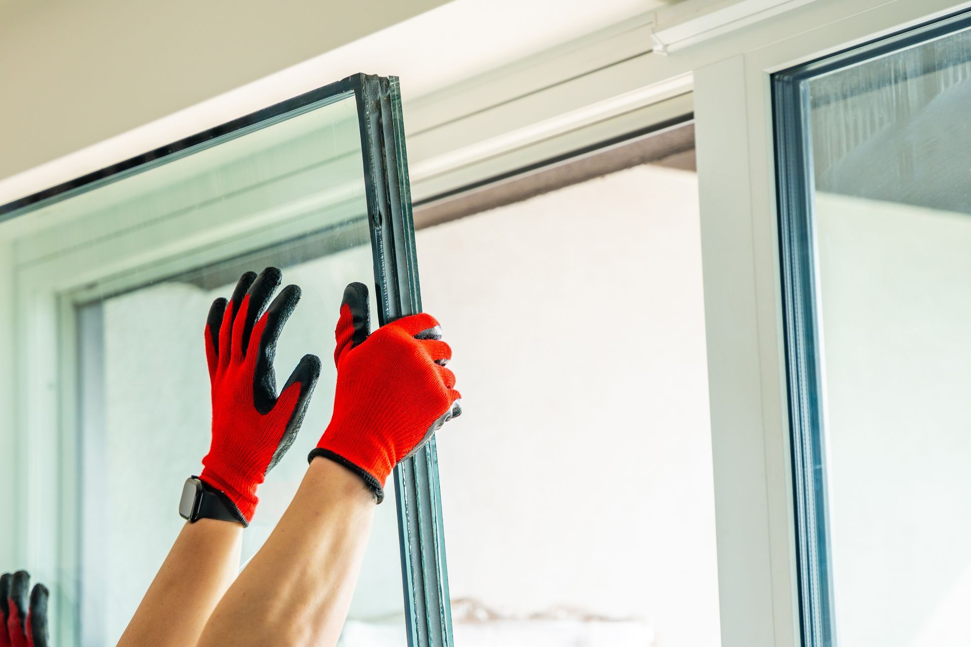Hands in red gloves adjusting a sliding window frame indoors