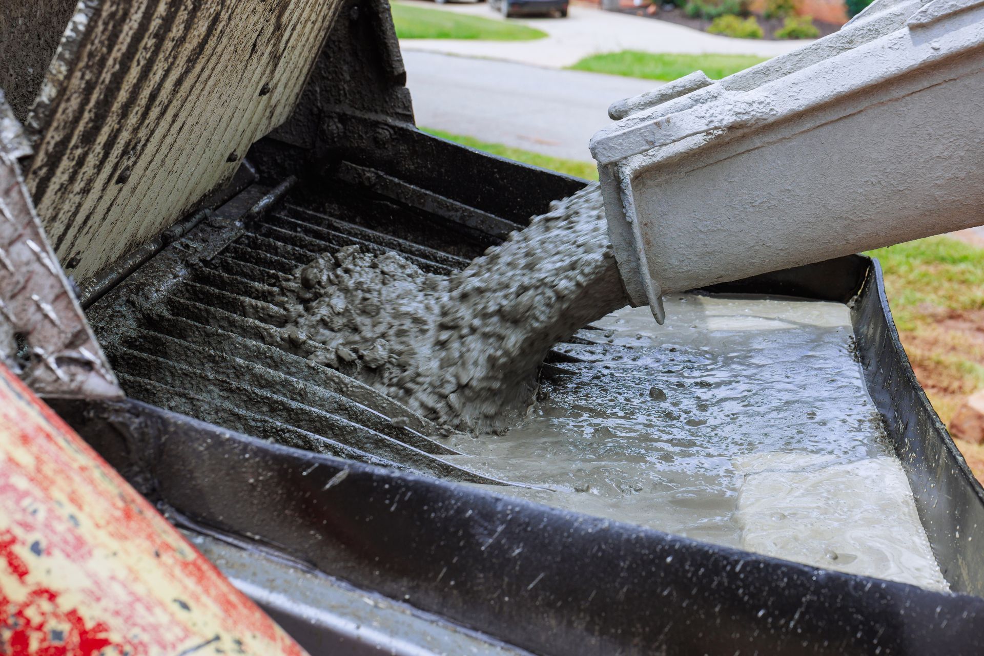 Concrete pouring into a black gutter channel beside a roadway