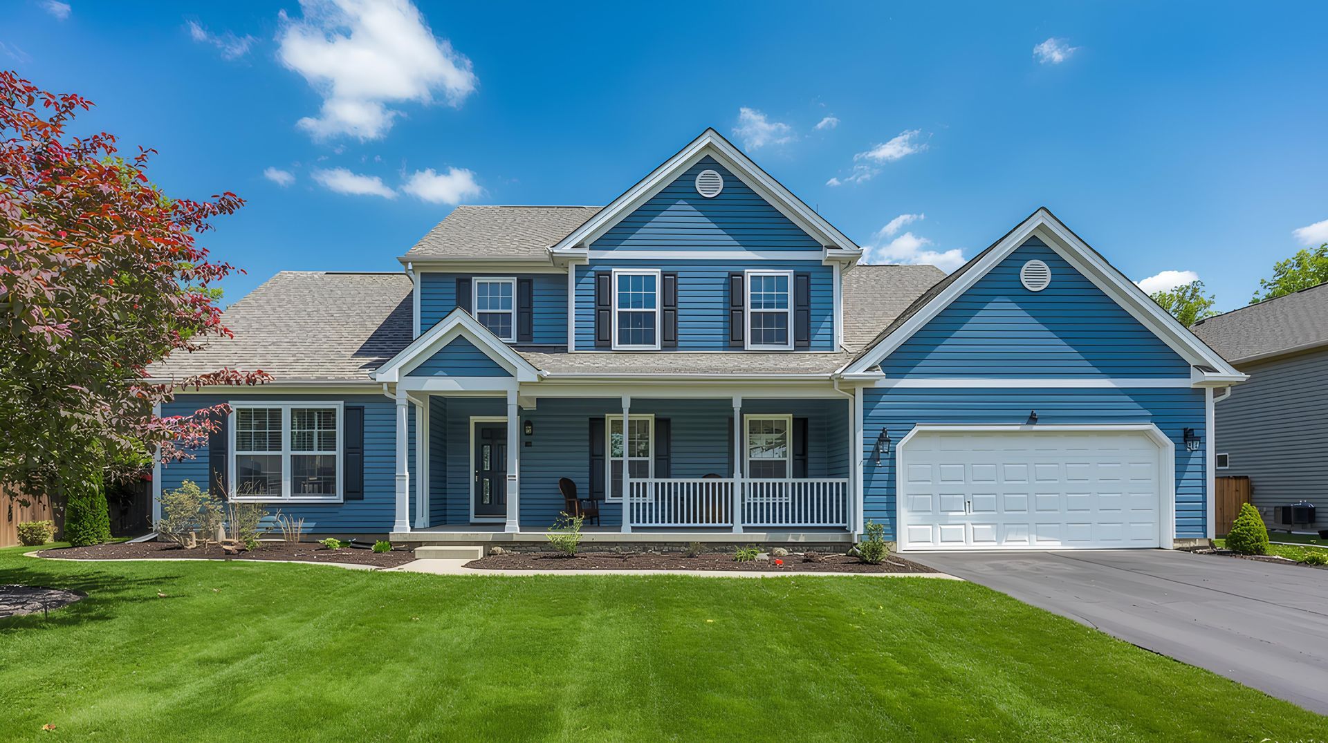 Blue two-story suburban house with a white garage, front porch, and manicured green lawn under a clear sky