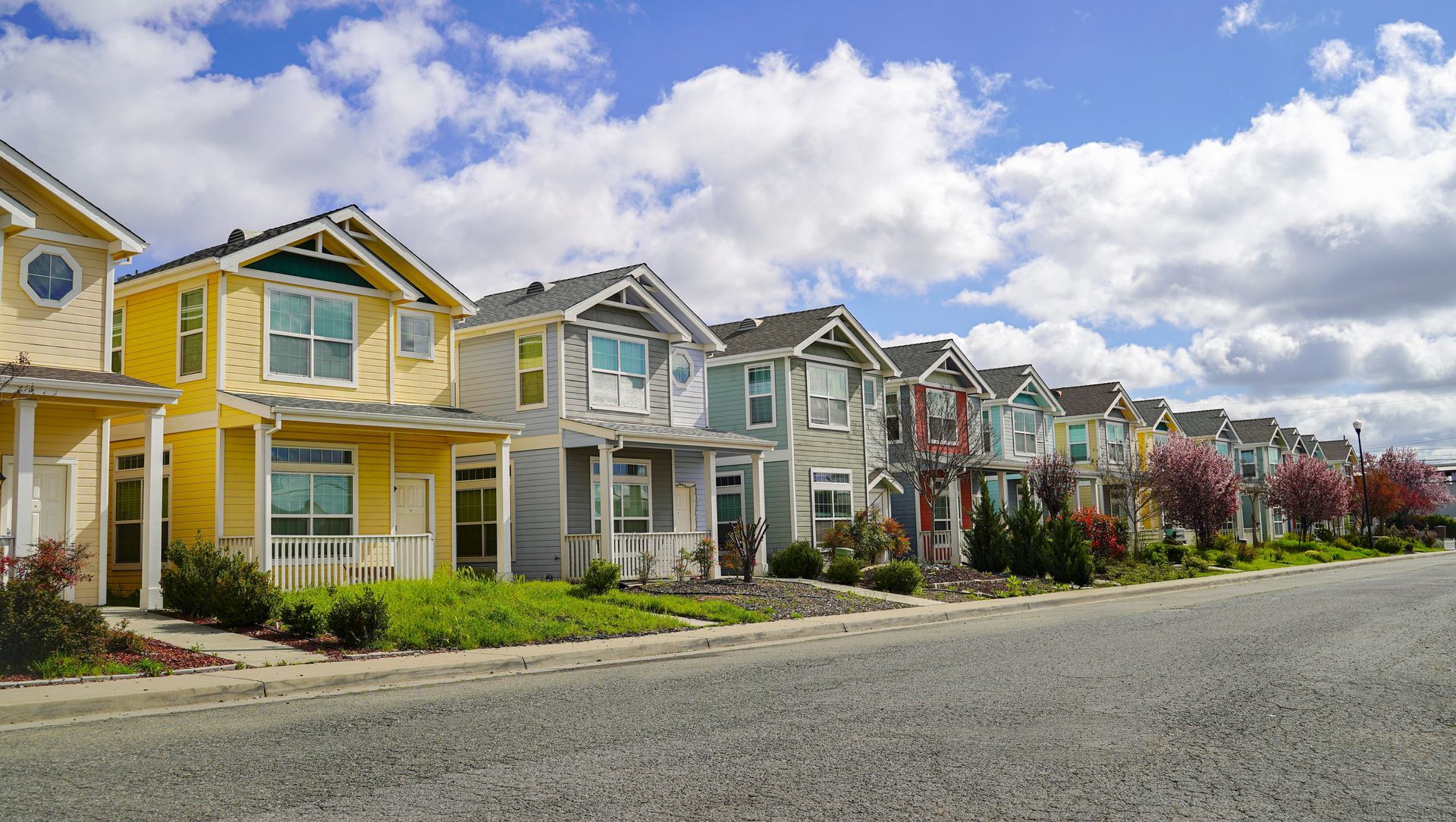 Row of colorful suburban houses along a quiet street under a cloudy sky
