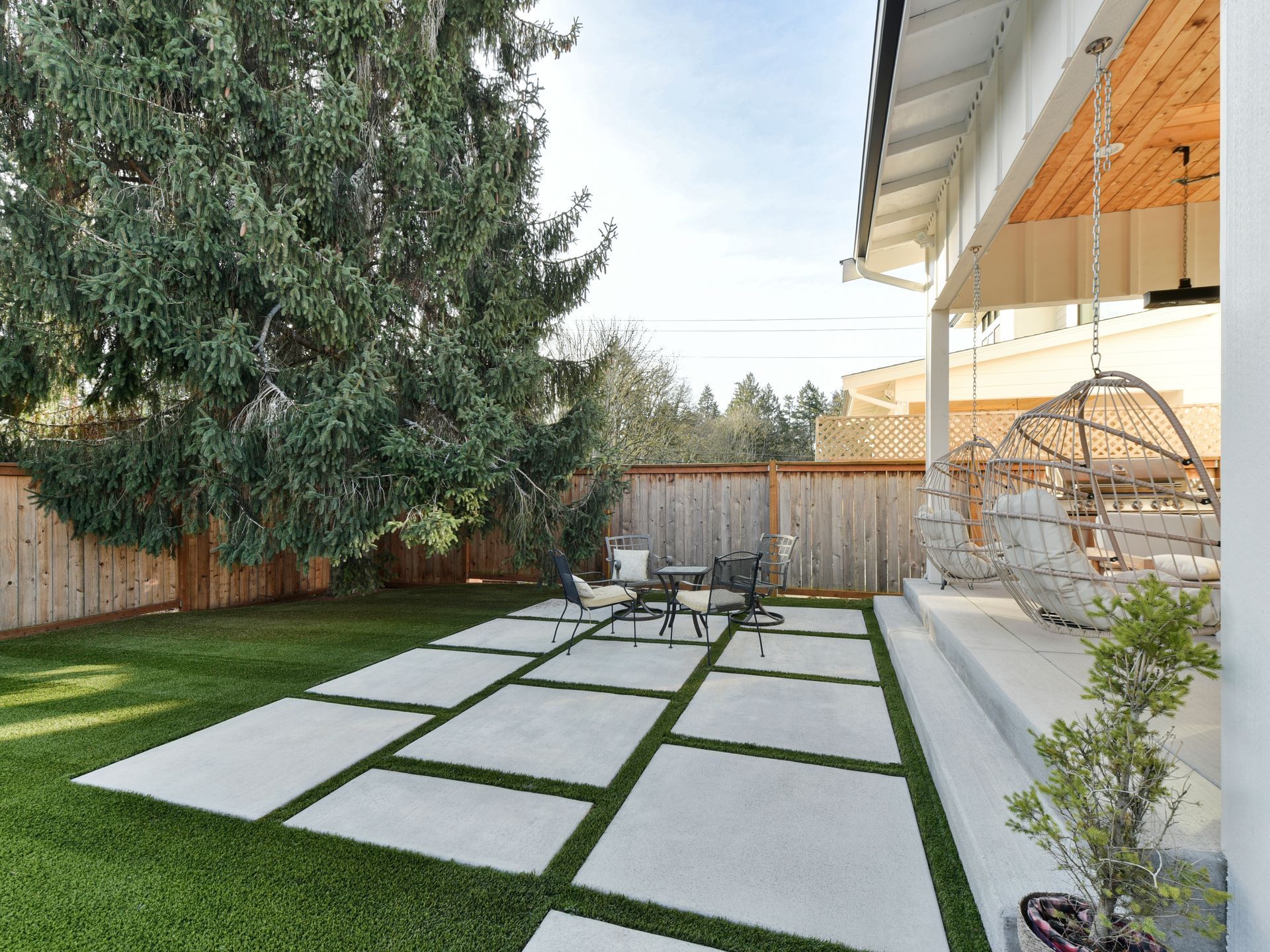 Backyard patio with large stepping stones, lawn, trees, and a covered seating area