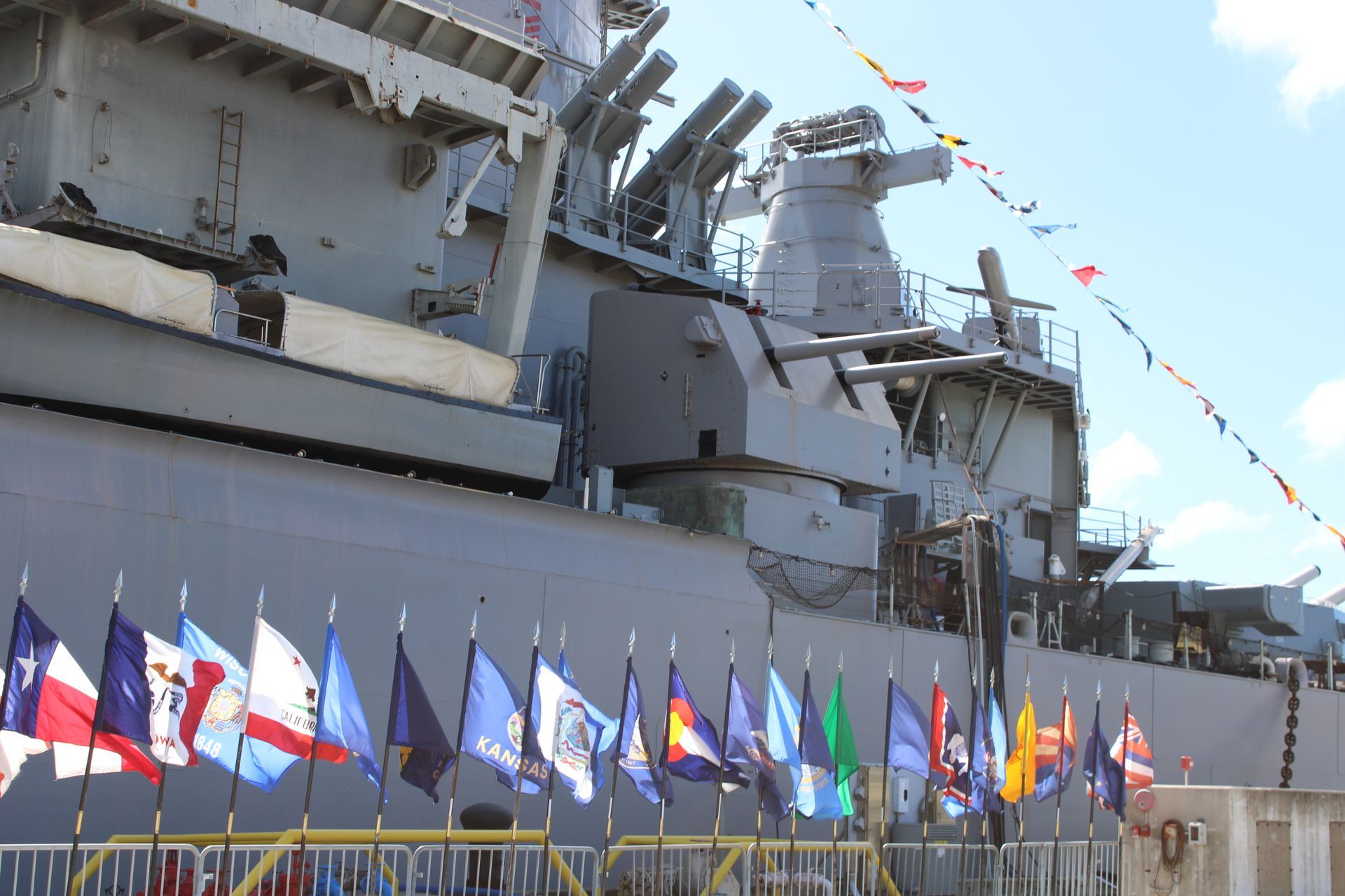 Large gray battleship, partially visible, with flags displayed below it.