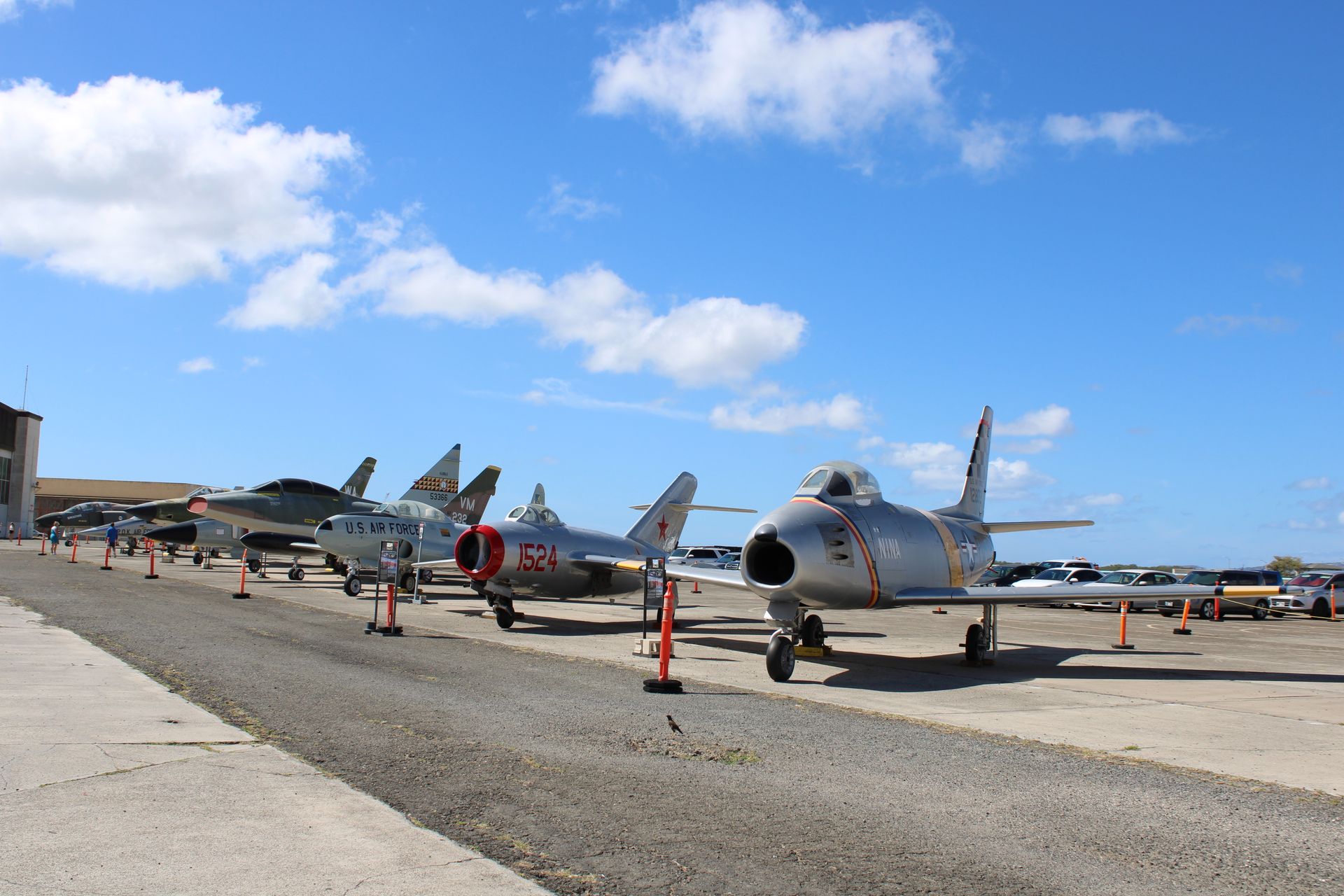 Jet fighters parked on a sunny tarmac under a blue sky with clouds
