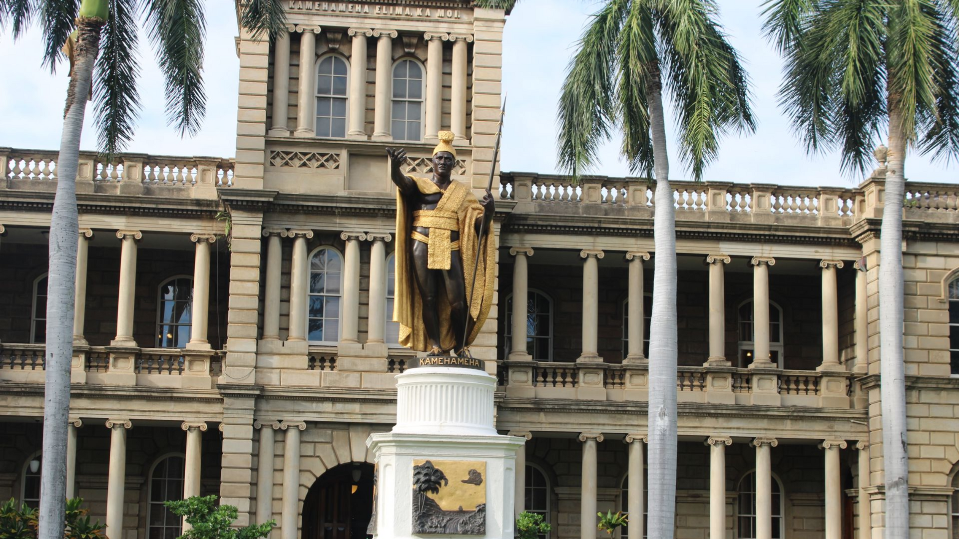 Up close image of the King Kamehameha I Statue in his gold cloak looking over the palace
