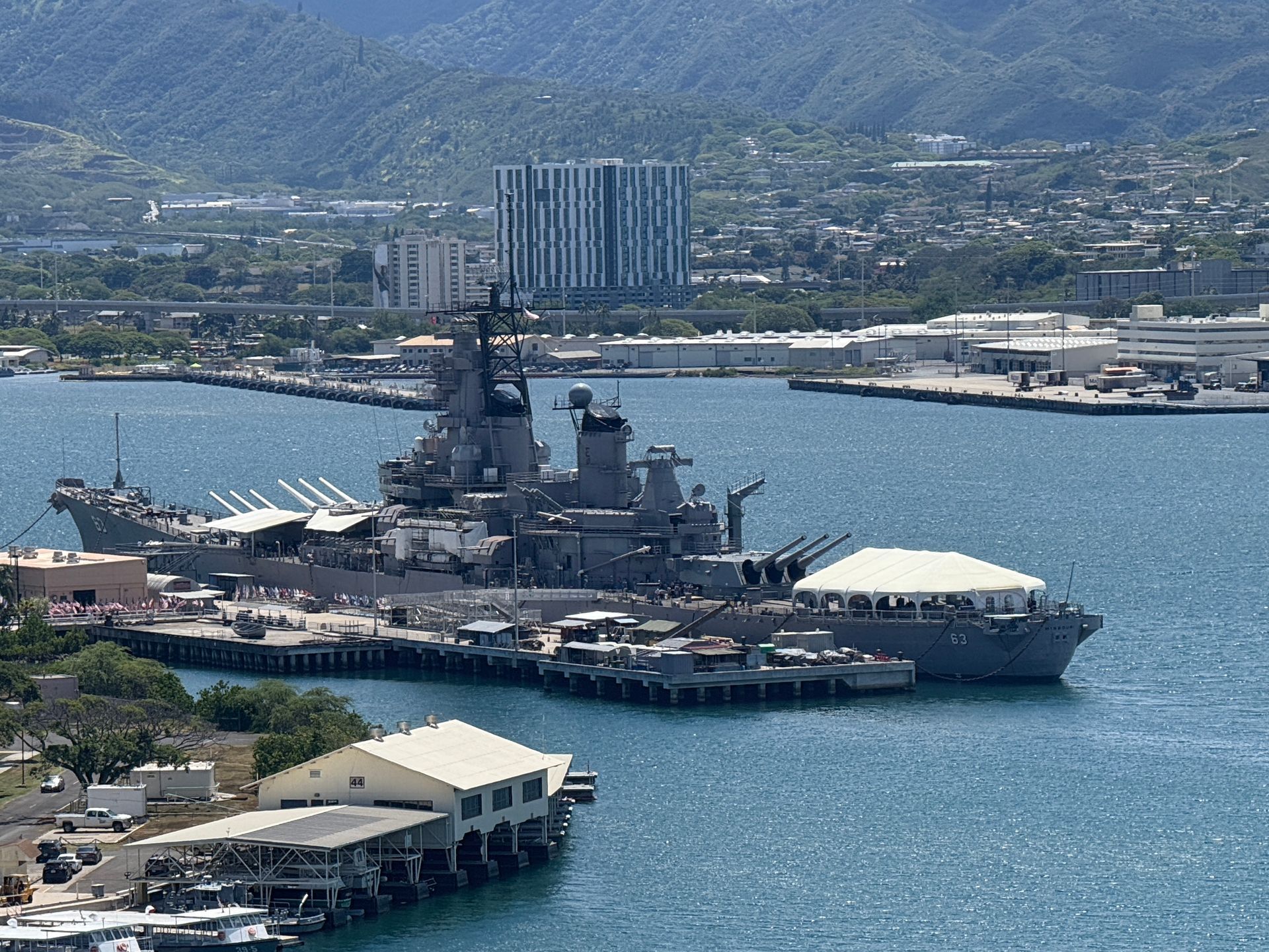 Battleship Missouri at Pearl Harbor, Hawaii. A large warship docked with buildings and a city in the background.