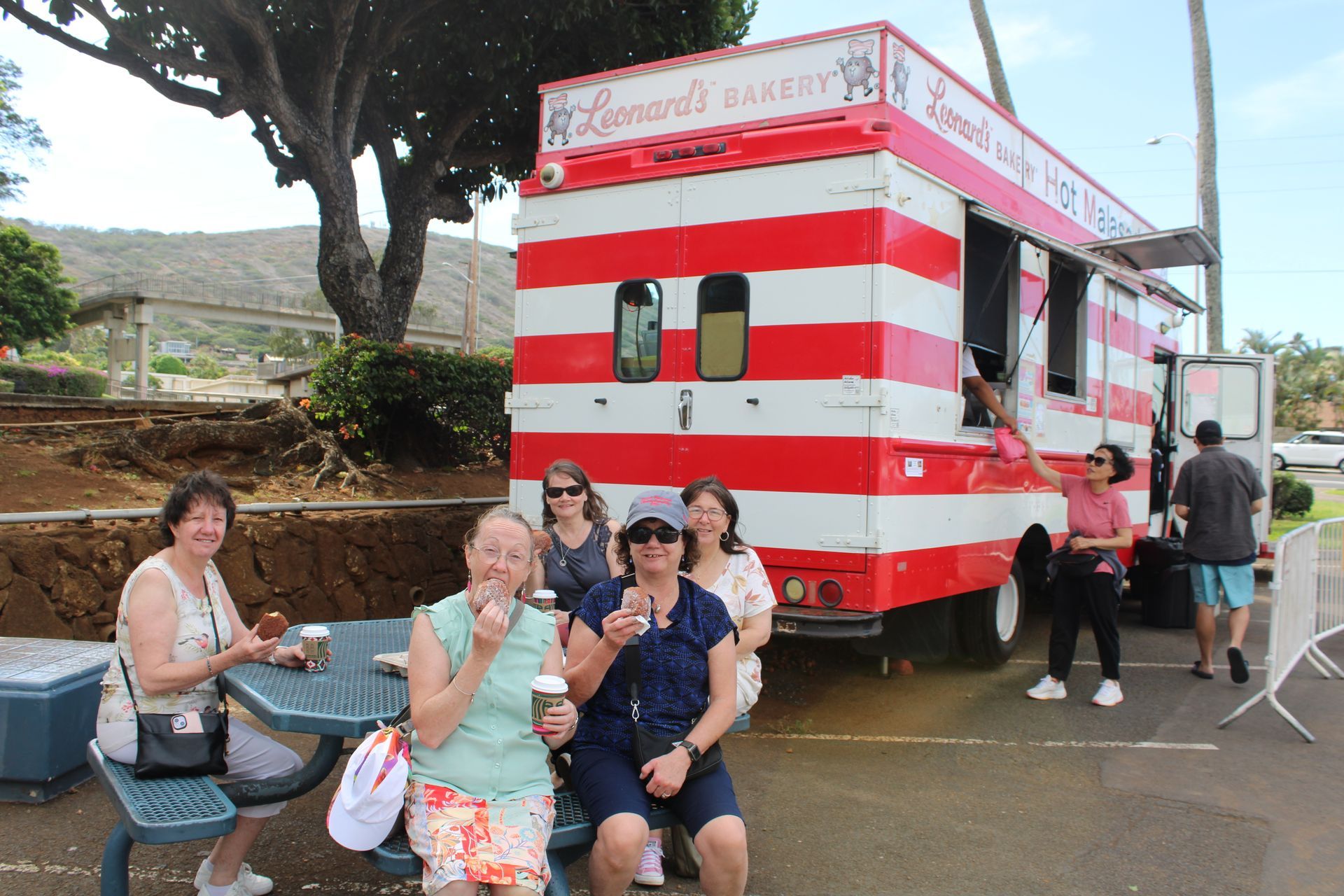 People sitting beside a red-and-white striped food truck at an outdoor event