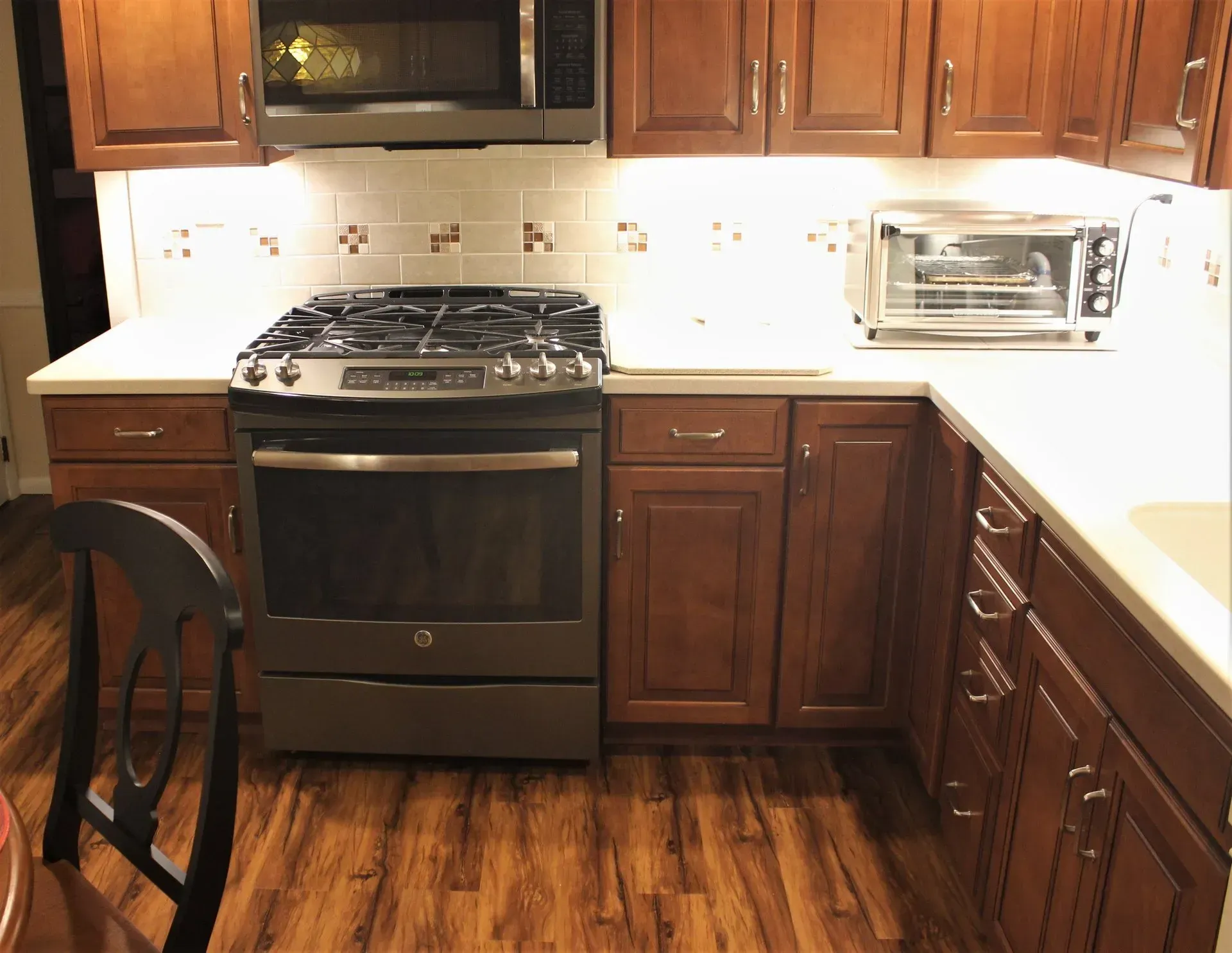 Modern kitchen with dark cabinets, stainless stove, white countertops, and a microwave on the right In Bucks County PA