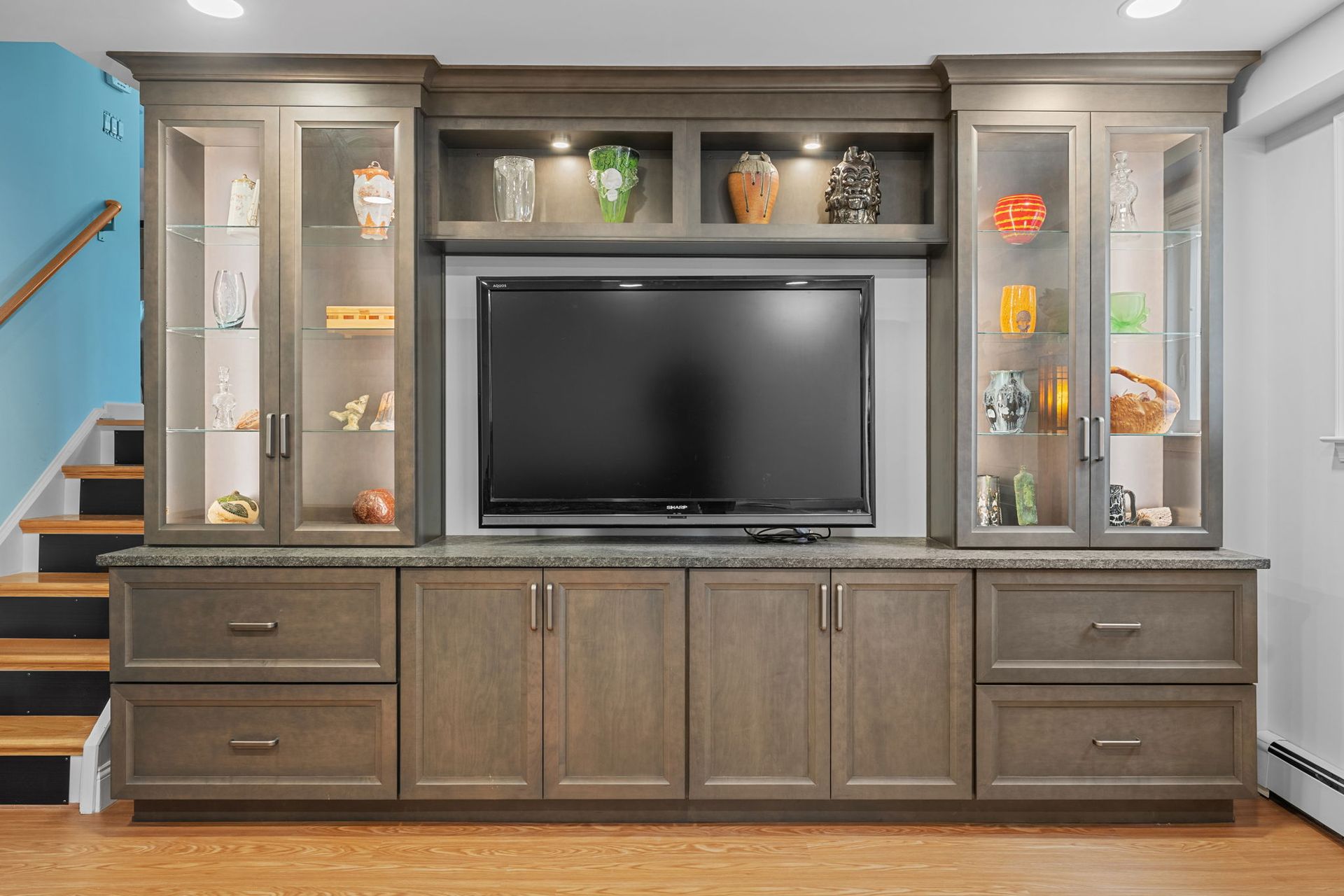 Gray built-in entertainment center with TV, cabinets, shelves, and decorative items In Bucks County PA 