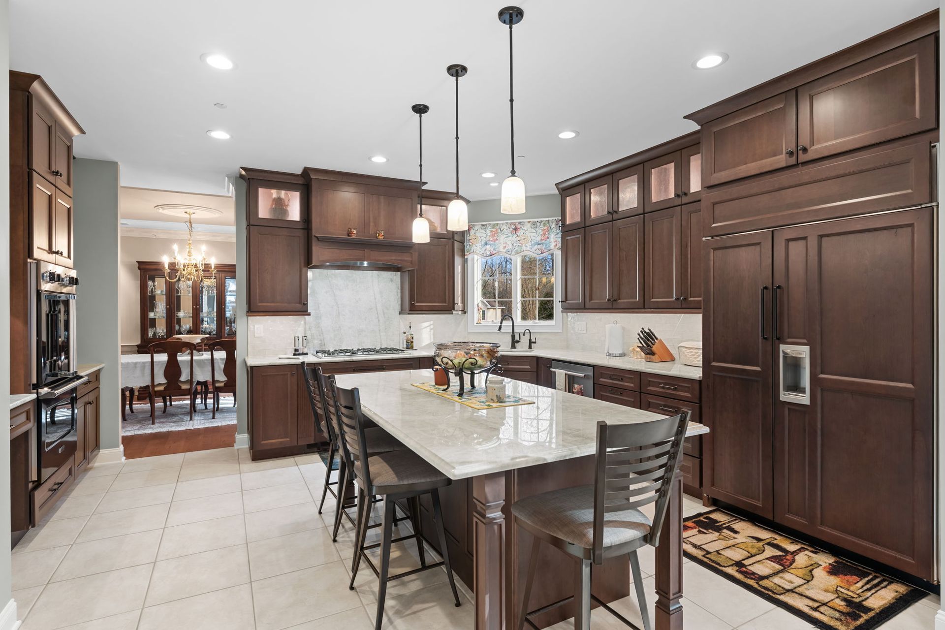Modern kitchen with dark wood cabinets, white island, pendant lights, and stainless steel appliances In Bucks Country PA