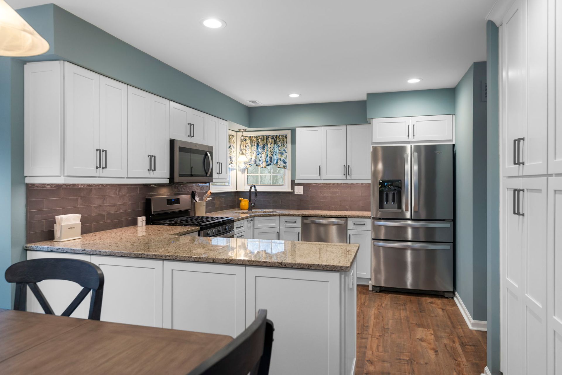 Modern kitchen with white cabinets, granite counters, stainless steel appliances, and wood floors In Bucks Country PA