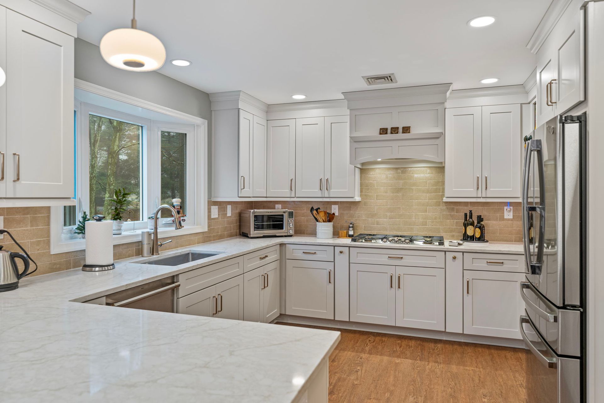 Bright modern white kitchen with island, stainless steel appliances, and large windows In Bucks County PA