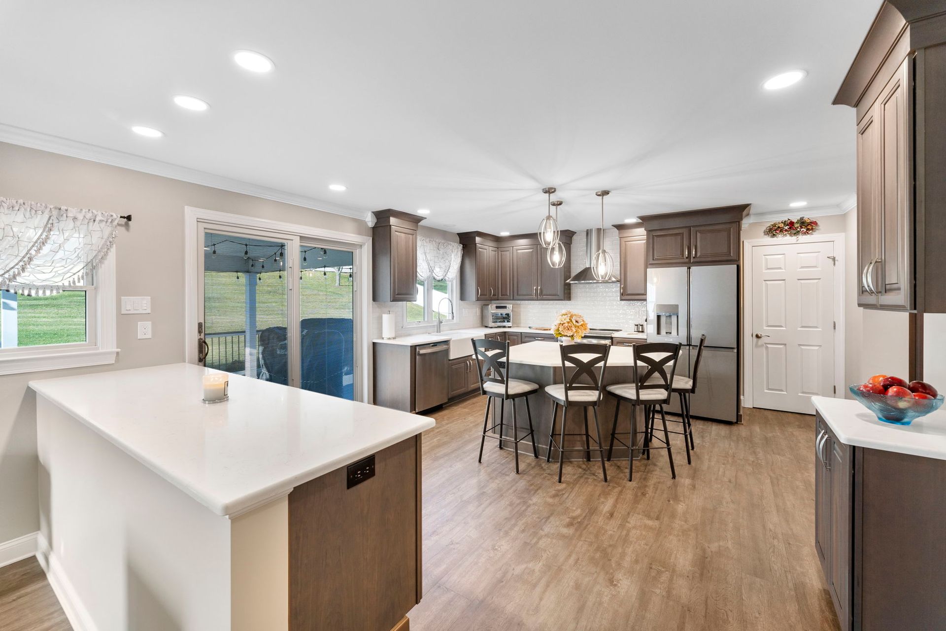 Bright modern kitchen and dining area with island, wood floors, stainless appliances, and sliding glass doors In Bucks Country PA
