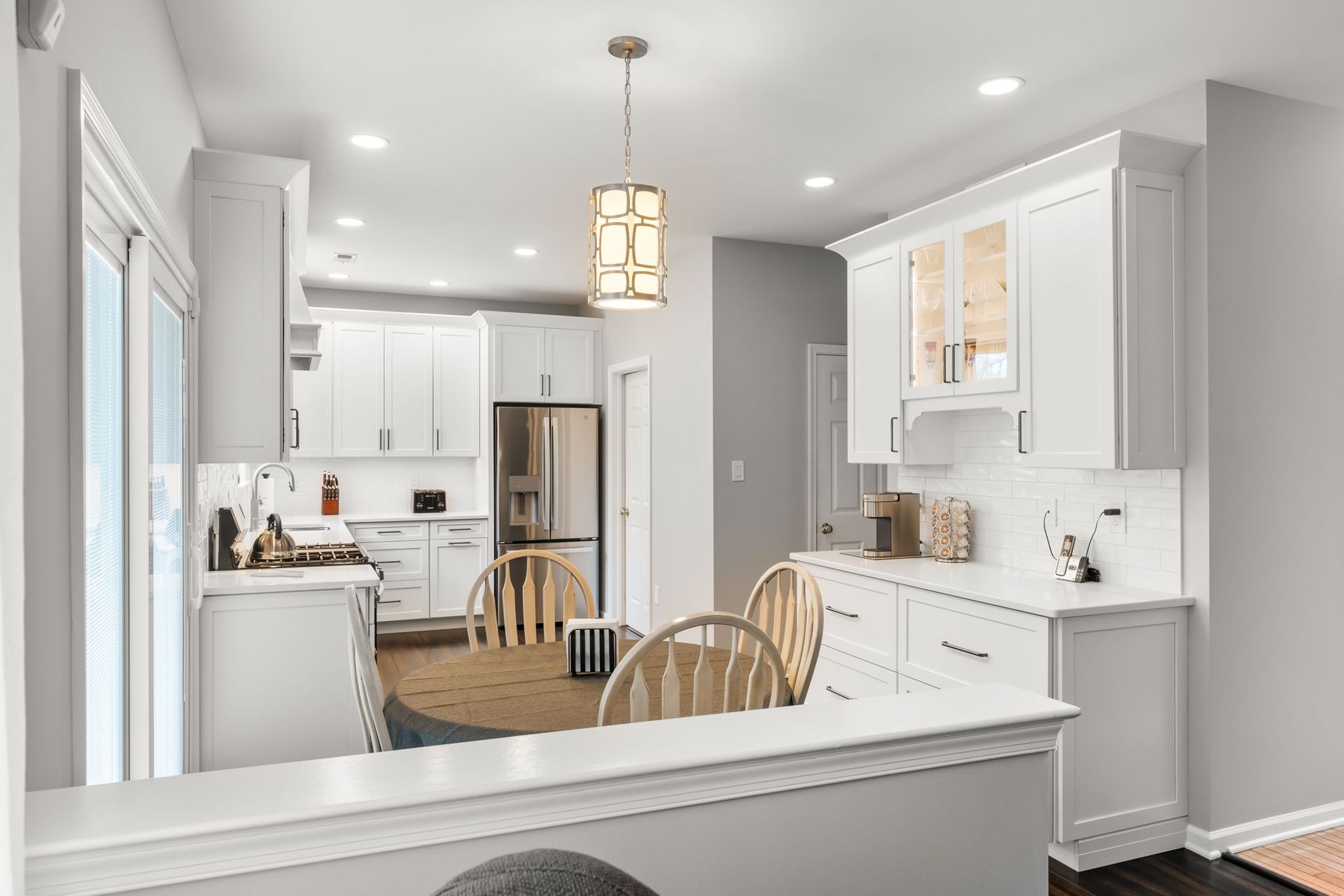 Bright white kitchen and dining area with light wood table, chairs, and stainless steel refrigerator  In Bucks County PA