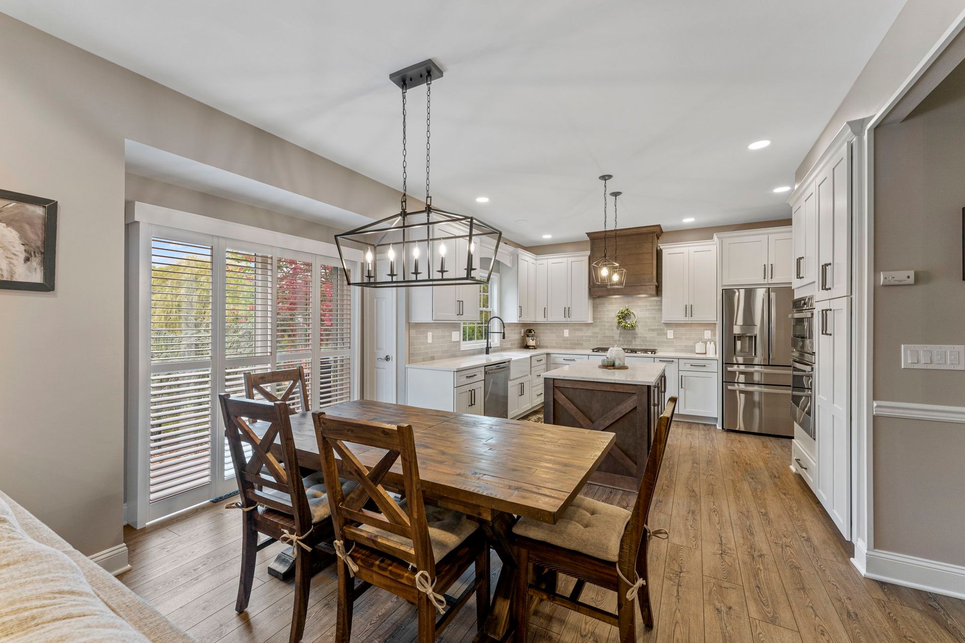 Open dining area with wooden table, chairs, and a bright modern kitchen with white cabinets  In Bucks County PA