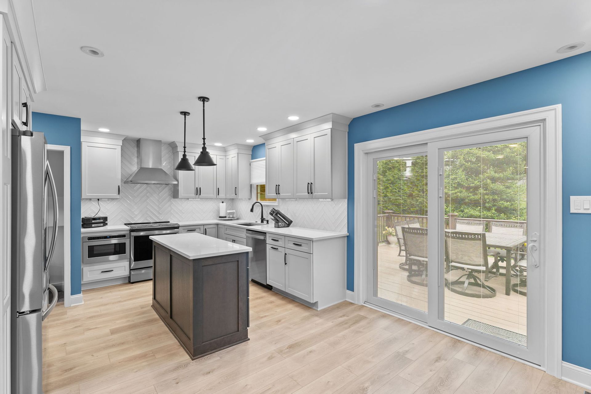 Bright modern kitchen with white cabinets, island, stainless appliances, and patio doors to a deck in Bucks County PA