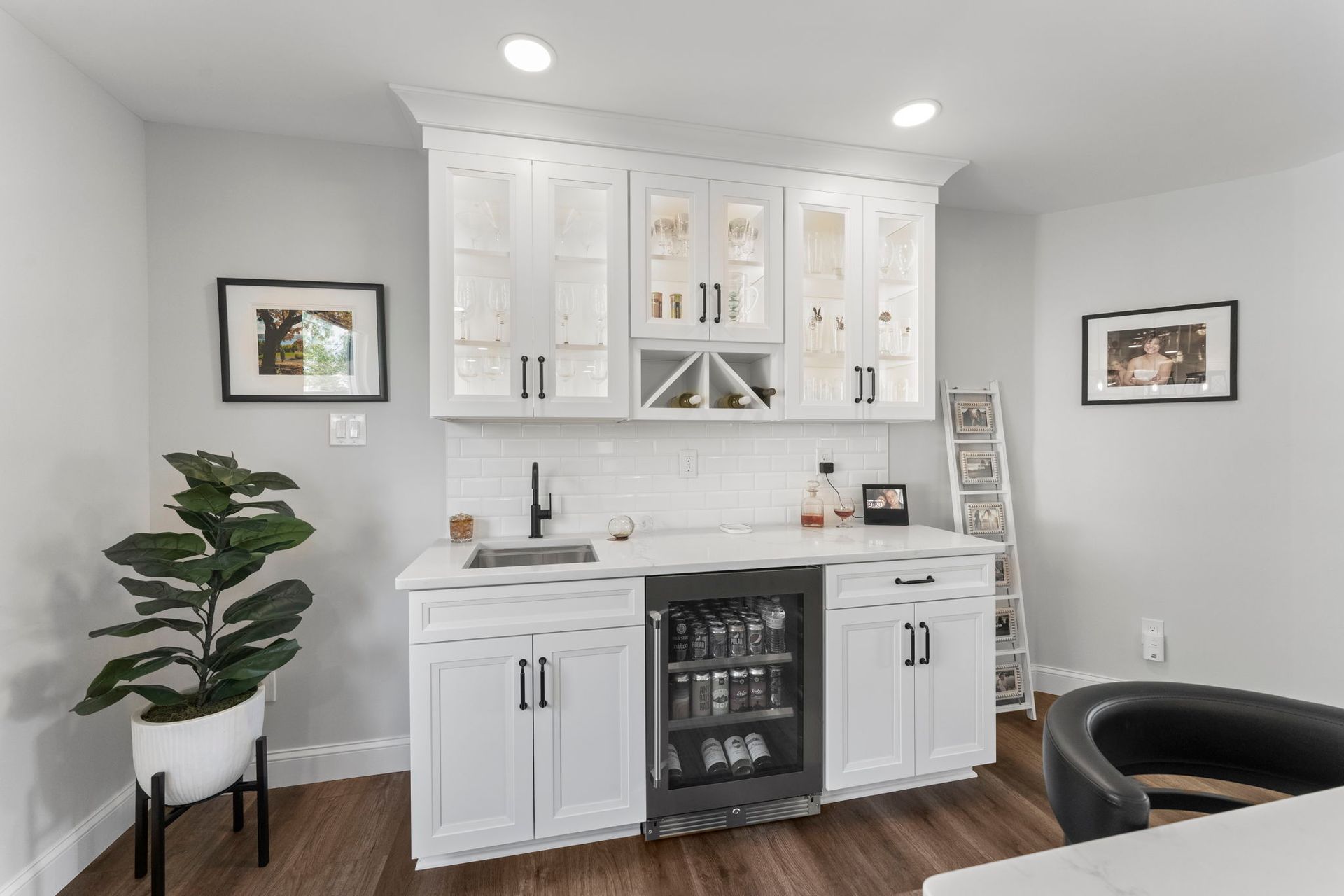 Bright white home bar with cabinets, wine fridge, potted plant, and dark wood floor In Bucks County PA