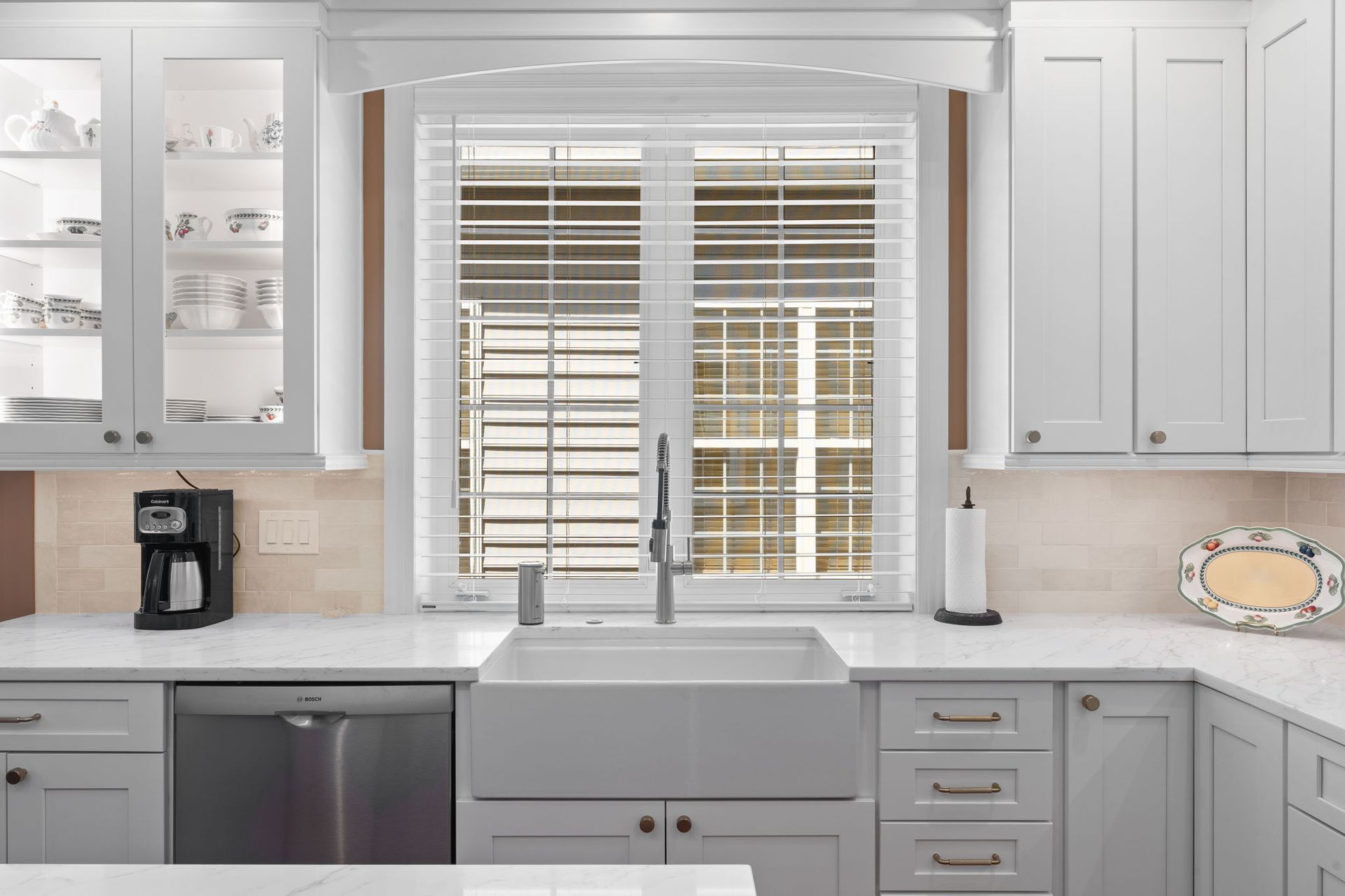 Bright white kitchen with gray cabinets, window over sink, and coffee maker on the counter In Bucks County PA