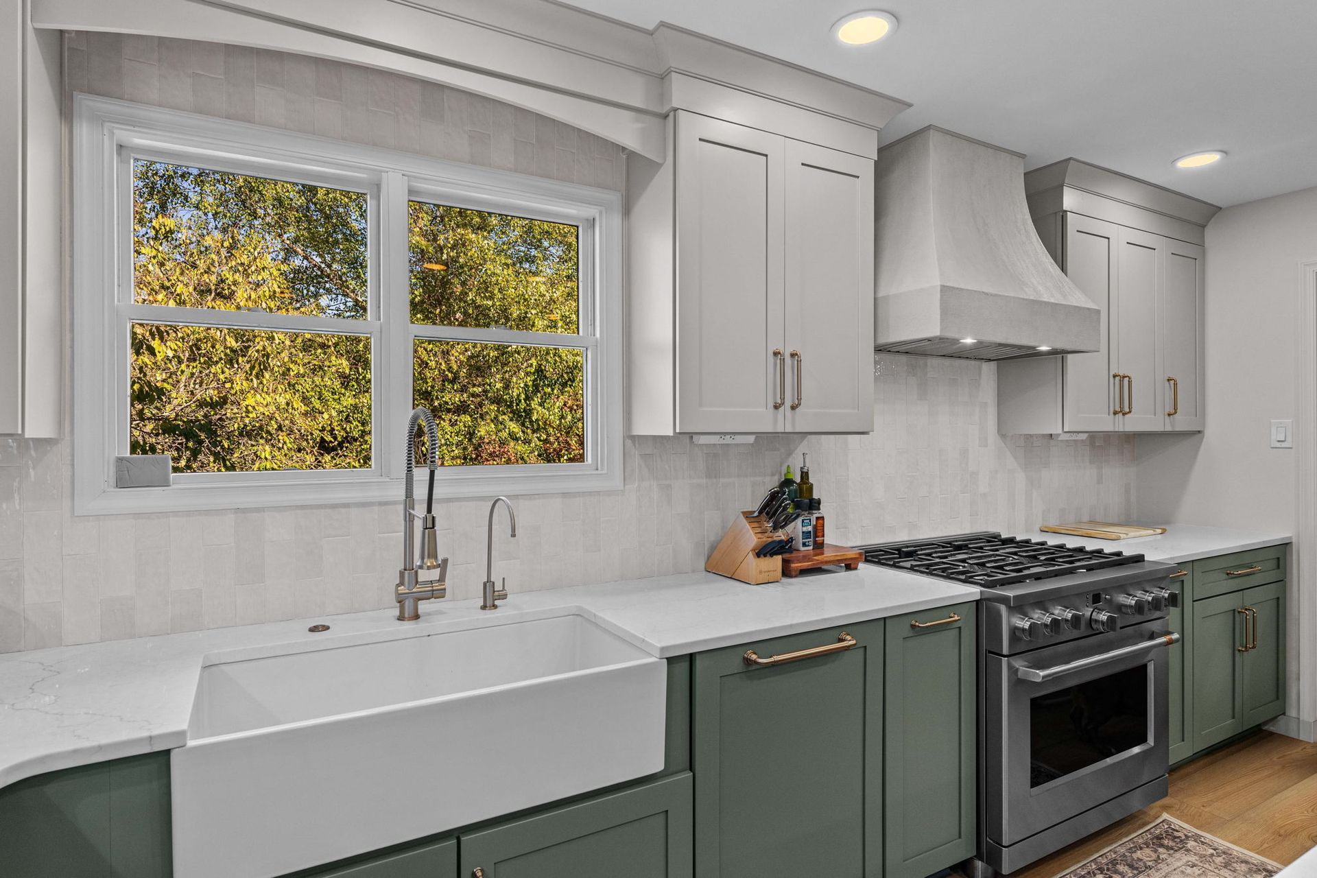 Bright modern kitchen with white cabinets, green lower cabinets, large window, and stainless gas range in Bucks County PA