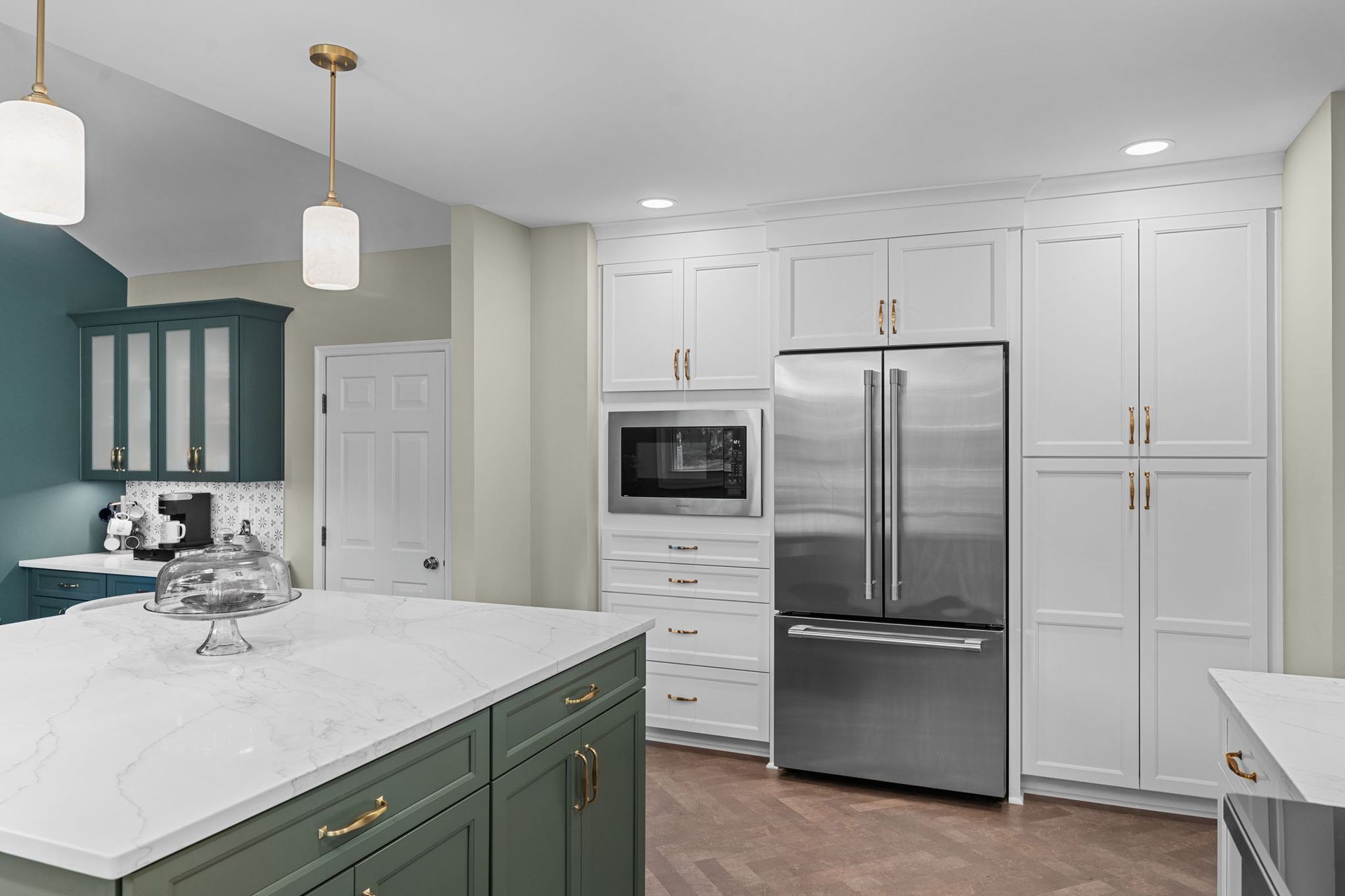 Bright modern kitchen with white cabinets, stainless fridge, and green island cabinets In Bucks County PA