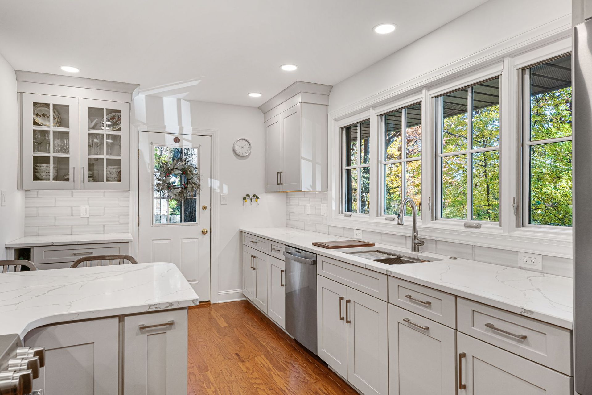 Bright white kitchen with marble counters, gray cabinets, wood floor, and large windows in Bucks Country PA
