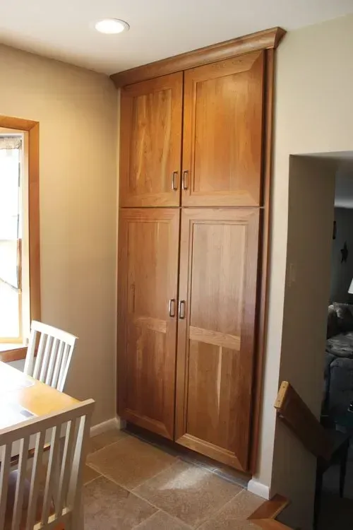 Tall wooden pantry cabinet beside a dining table in a kitchen or dining area In Richboro PA