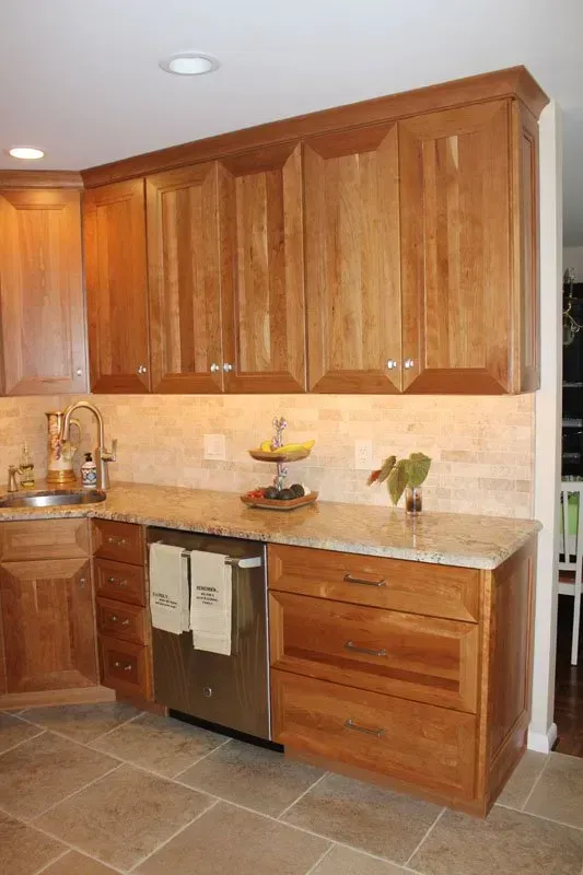 Wooden kitchen cabinets, beige tile backsplash, and stainless steel dishwasher in a warm-toned kitchen
In Richboro PA
