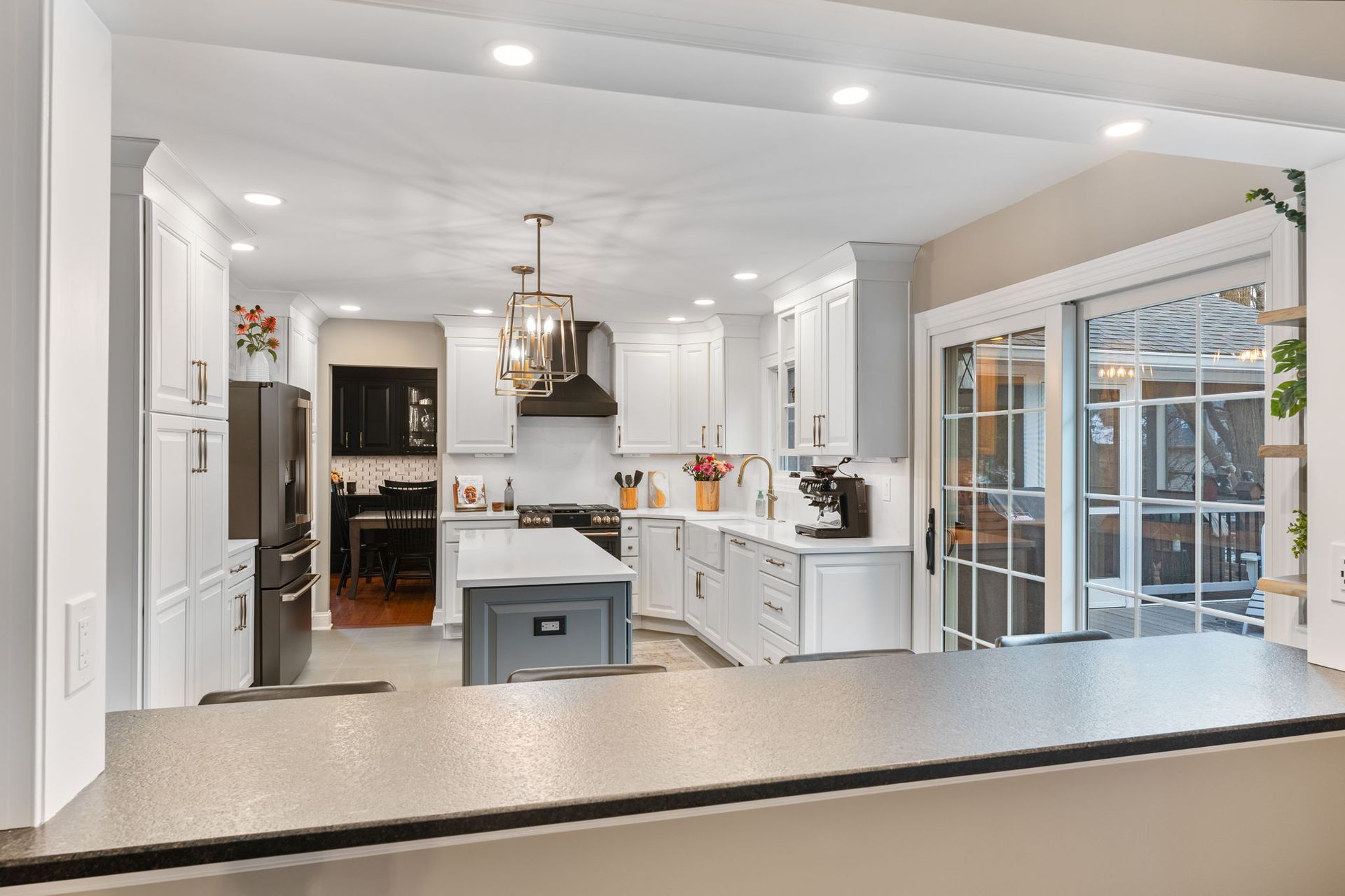Bright modern kitchen with white cabinets, island, pendant light, and glass doors to a patio In Bucks Country PA