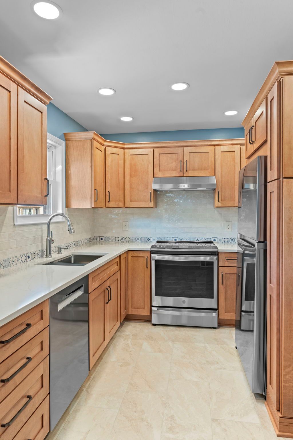 Bright kitchen with wooden cabinets, granite counters, stainless stove, and recessed ceiling lights In Bucks County PA
