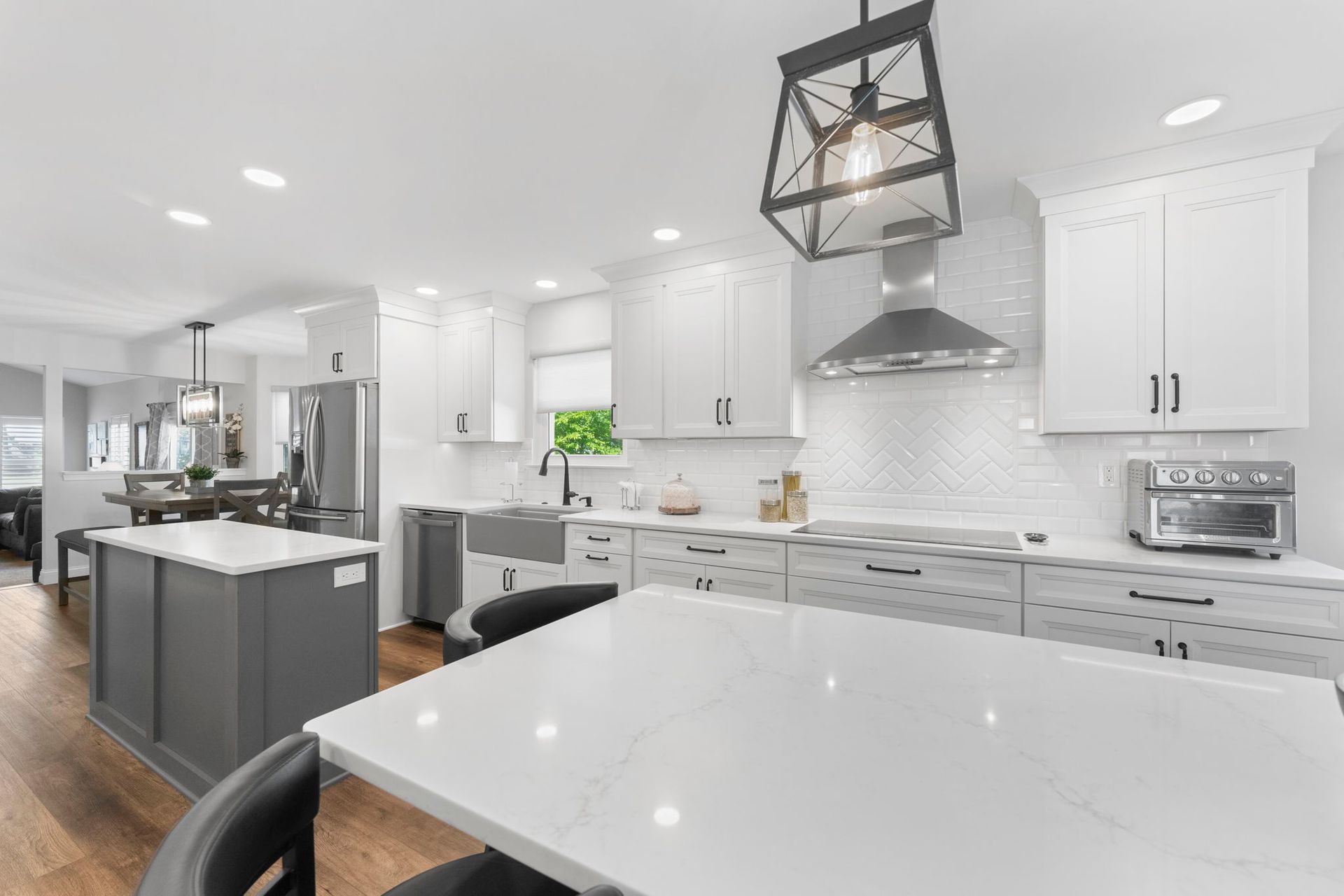 Bright white modern kitchen with island, stainless steel appliances, and pendant lights In Bucks County PA