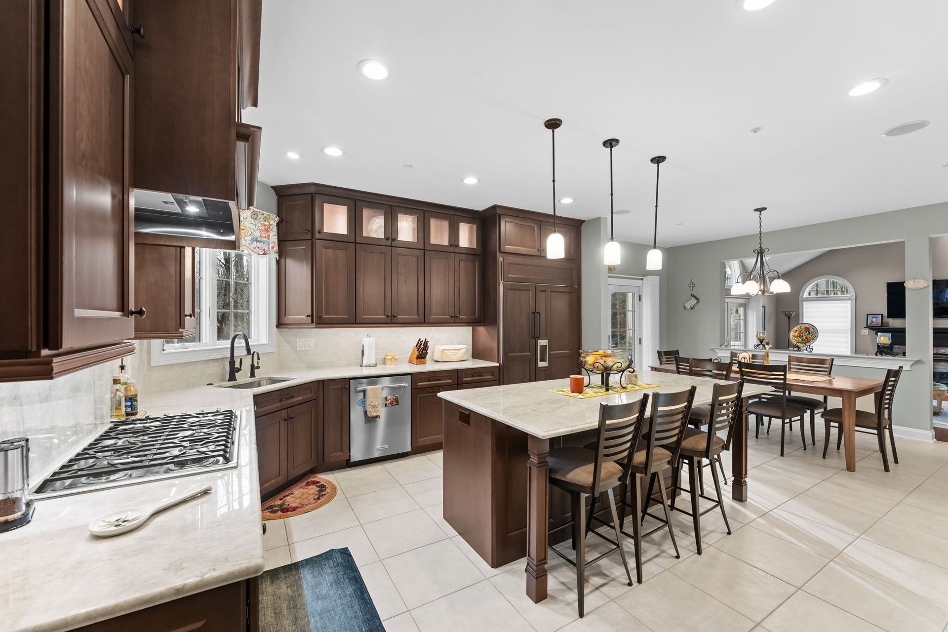 Bright modern kitchen with dark wood cabinets, white counters, and a central island with bar stools In Bucks Country PA