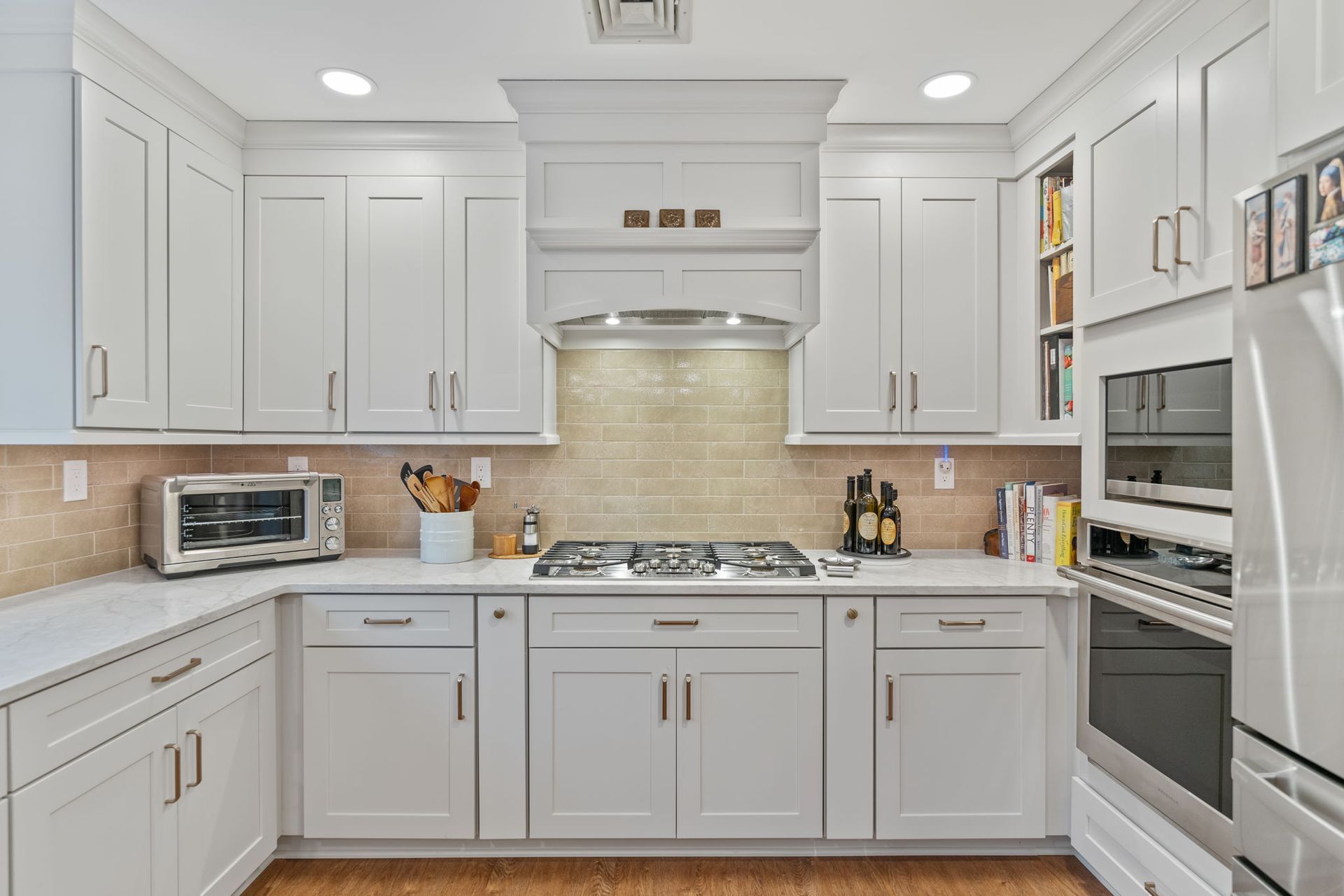 Bright white kitchen with gray cabinets, beige backsplash, and stainless steel appliances In Bucks County PA